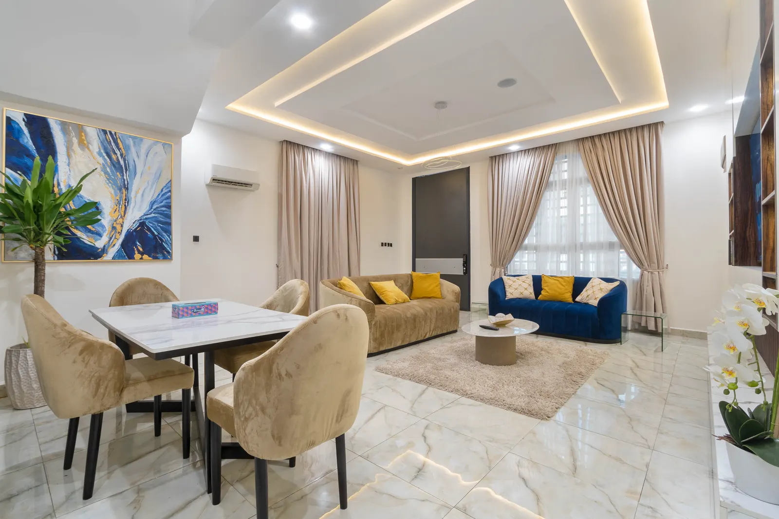 Spacious living room at Aduni's Place with blue seating and a dining area